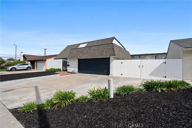 view of front of home featuring a garage, a shingled roof, concrete driveway, a gate, and fence