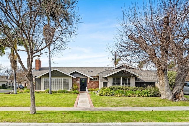 view of front facade with a shingled roof and a front yard