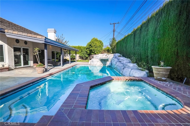 view of swimming pool featuring a patio area, fence, and an in ground hot tub