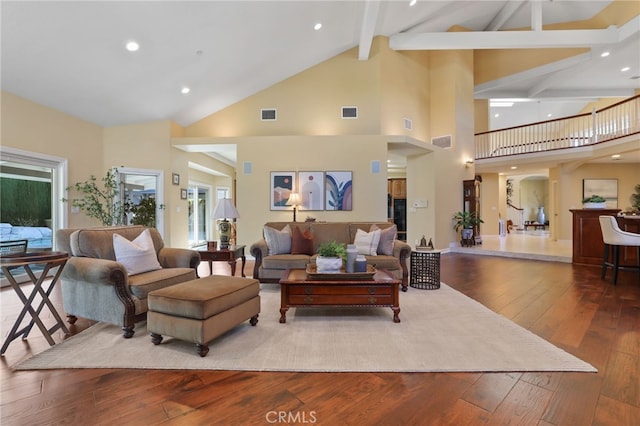 living room with beam ceiling, visible vents, and wood finished floors