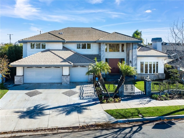 view of front of property with driveway, an attached garage, fence, and a tiled roof