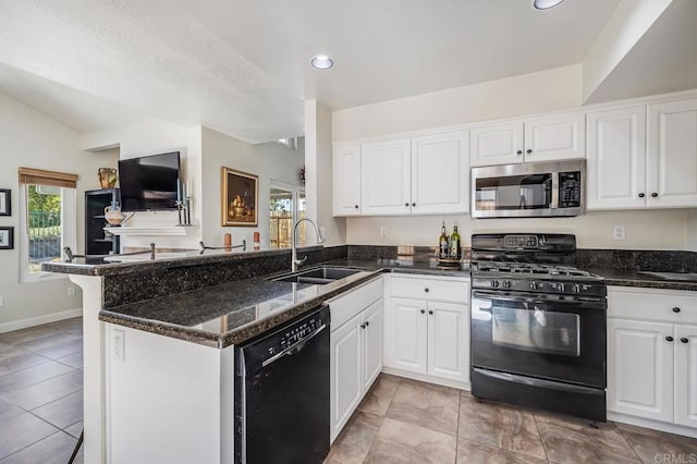 kitchen with dark stone counters, white cabinets, a peninsula, black appliances, and a sink