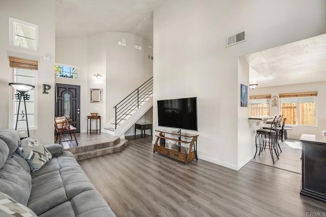 living room with a wealth of natural light, visible vents, stairway, and wood finished floors