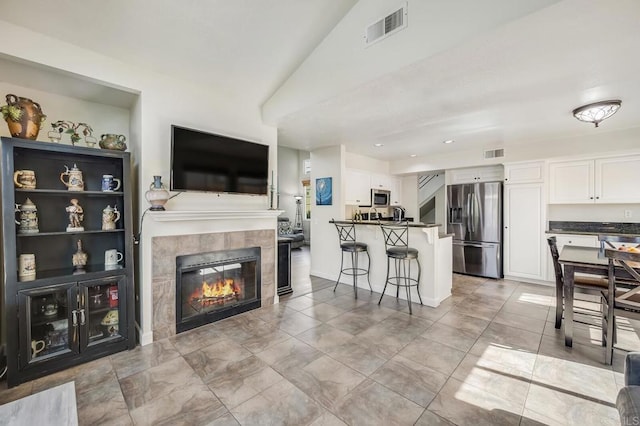 living area featuring vaulted ceiling, visible vents, and a fireplace