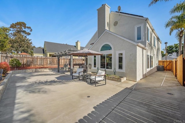 rear view of house featuring a patio area, a pergola, a fenced backyard, and stucco siding