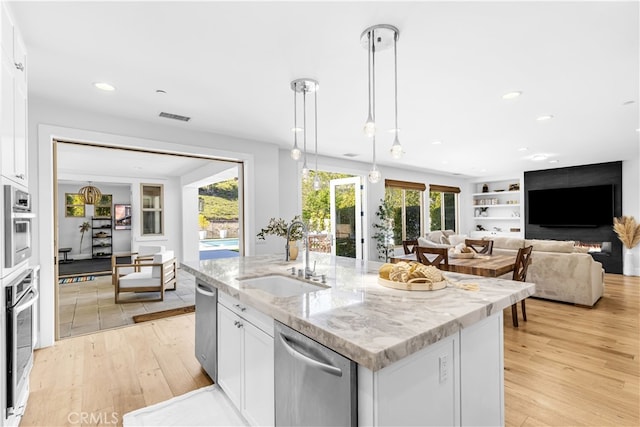 kitchen with stainless steel appliances, light wood finished floors, a sink, and visible vents