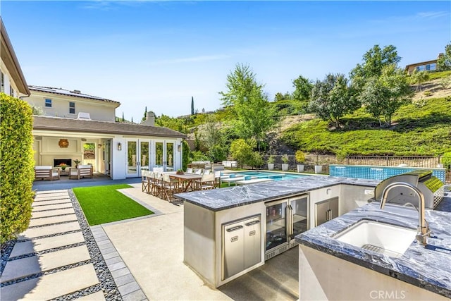 view of patio / terrace with a fenced in pool, fence, exterior kitchen, outdoor lounge area, and a sink