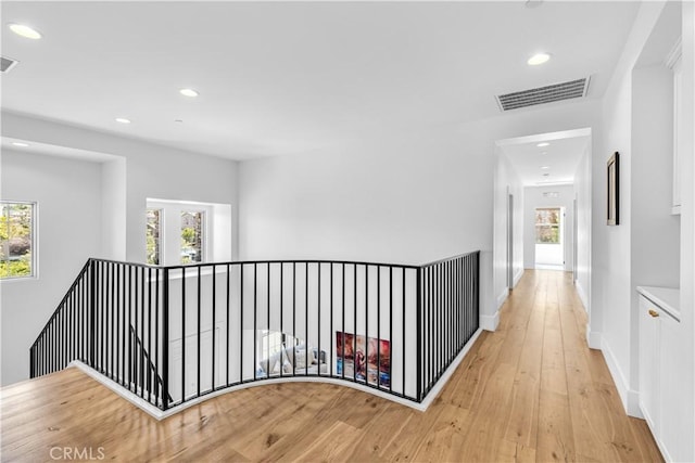 hall featuring light wood-style floors, recessed lighting, visible vents, and baseboards