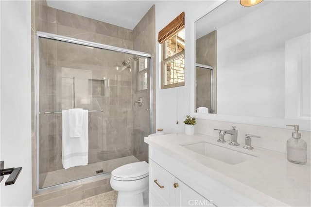 bathroom with a shower stall, toilet, and vanity