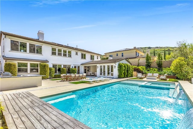 view of pool with a pool with connected hot tub, french doors, a patio area, and an outdoor living space