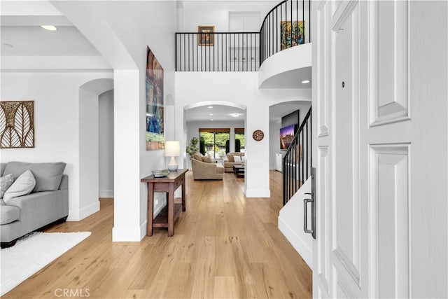 foyer with light wood-style flooring, a high ceiling, stairway, and baseboards