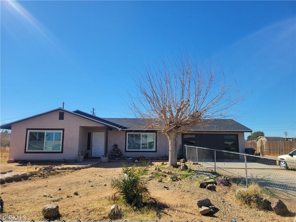 single story home with driveway, an attached garage, fence, and stucco siding