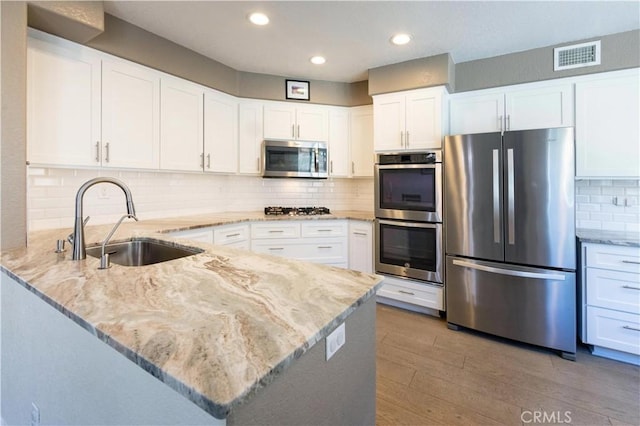 kitchen featuring visible vents, white cabinets, a peninsula, light stone countertops, and stainless steel appliances