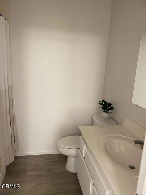 bathroom with toilet, baseboards, wood finished floors, and vanity