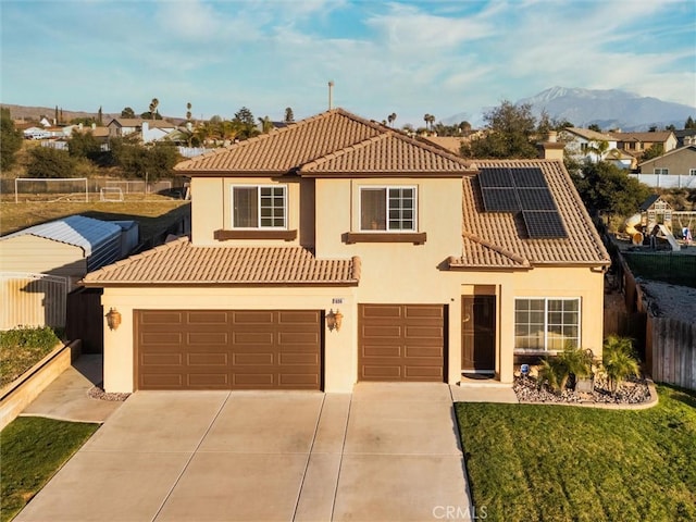 mediterranean / spanish house featuring a tile roof, fence, solar panels, and stucco siding