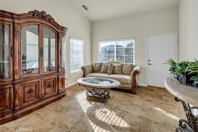 sitting room with baseboards, visible vents, and vaulted ceiling