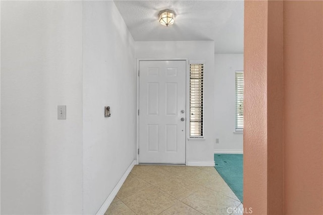 foyer entrance featuring light tile patterned floors and baseboards