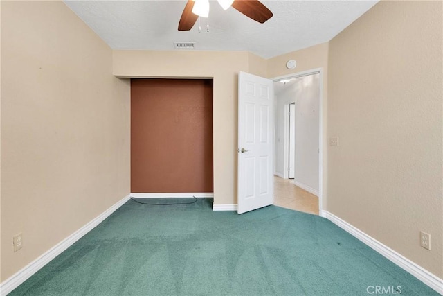 unfurnished bedroom featuring carpet floors, baseboards, visible vents, and a ceiling fan