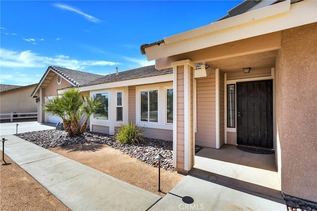 property entrance featuring fence and stucco siding