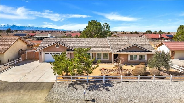 ranch-style home featuring driveway, fence, a mountain view, and stucco siding