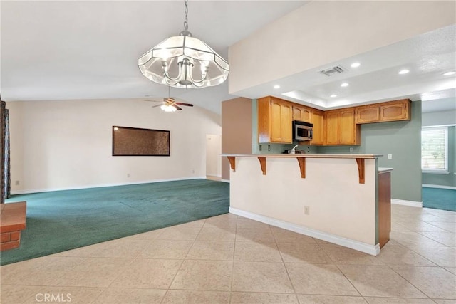 kitchen with light carpet, light countertops, stainless steel microwave, and open floor plan