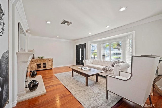 living room featuring recessed lighting, visible vents, light wood-type flooring, crown molding, and baseboards