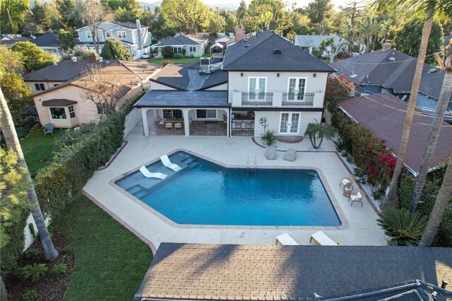 back of property with a patio area, a balcony, a shingled roof, french doors, and stucco siding