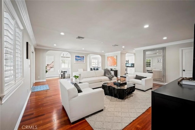 living room featuring arched walkways, ornamental molding, wood finished floors, and recessed lighting