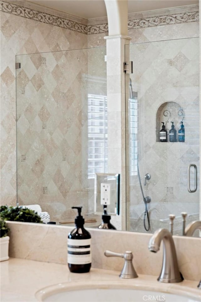 full bath with a shower stall, ornamental molding, a sink, and decorative columns