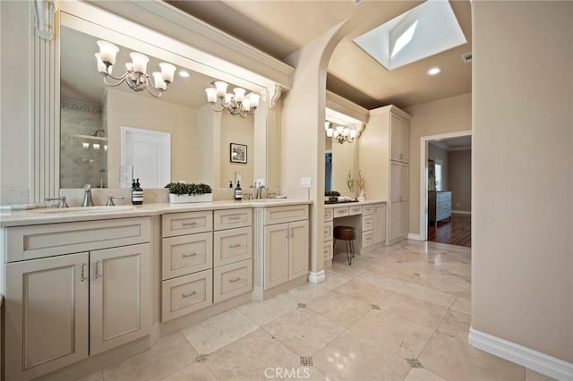 bathroom featuring a tile shower, a chandelier, double vanity, and a sink