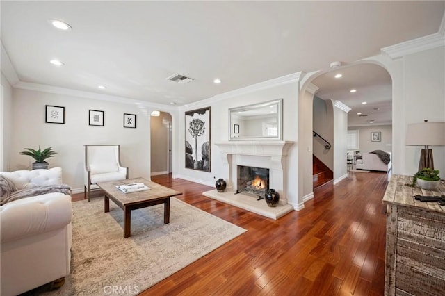 living area featuring a glass covered fireplace, visible vents, arched walkways, and recessed lighting