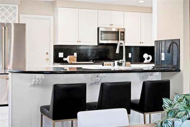 kitchen with stainless steel appliances, white cabinetry, a breakfast bar area, and tasteful backsplash