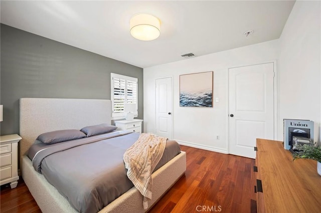 bedroom with baseboards, visible vents, and dark wood-style floors