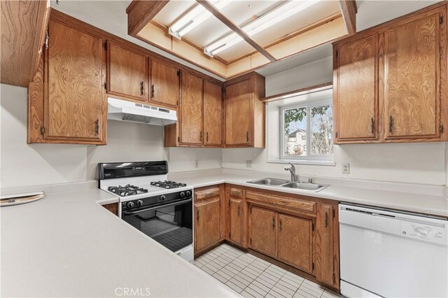 21013 Carriage Dr, Tehachapi, CA 93561 - kitchen featuring gas range oven, white dishwasher, light countertops, under cabinet range hood, and a sink
