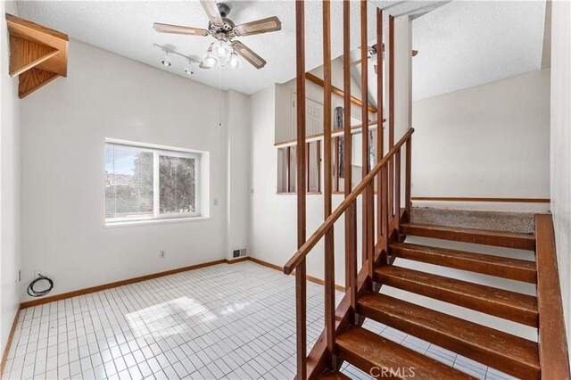 21013 Carriage Dr, Tehachapi, CA 93561 - staircase featuring ceiling fan, a textured ceiling, baseboards, and tile patterned floors