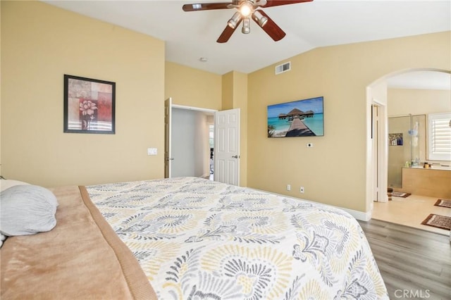 bedroom featuring arched walkways, wood finished floors, visible vents, a ceiling fan, and vaulted ceiling