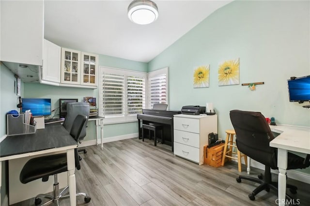 office area with vaulted ceiling, baseboards, and light wood-style floors