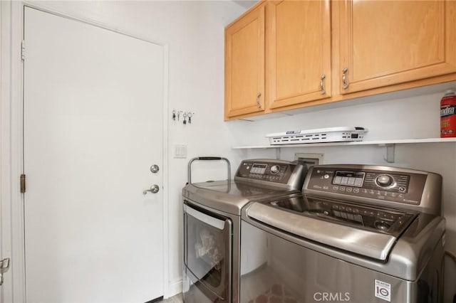 washroom featuring cabinet space and washer and clothes dryer