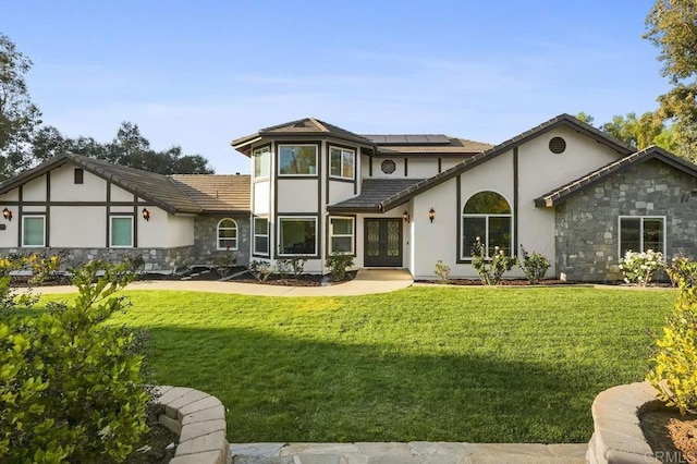 view of front of house with solar panels, a front lawn, stone siding, and stucco siding