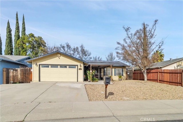 ranch-style house featuring an attached garage, driveway, fence, and solar panels