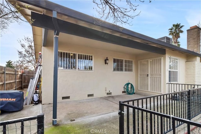 rear view of property featuring a chimney, crawl space, fence private yard, a patio area, and stucco siding