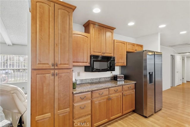 kitchen featuring stainless steel fridge, dark stone counters, light wood-style floors, black microwave, and recessed lighting