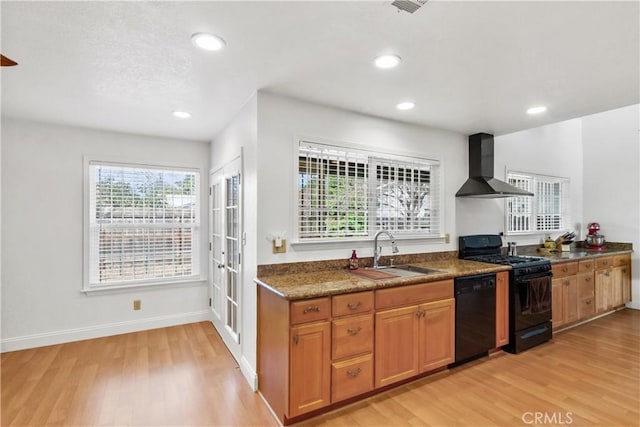 kitchen with a sink, wall chimney range hood, brown cabinets, black appliances, and dark countertops