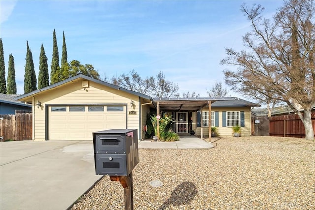 ranch-style house featuring a garage, concrete driveway, and fence