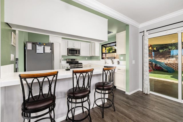 kitchen with white cabinets, a peninsula, stainless steel appliances, and light countertops