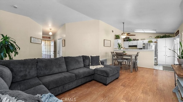 living room with vaulted ceiling, visible vents, light wood-type flooring, and a ceiling fan