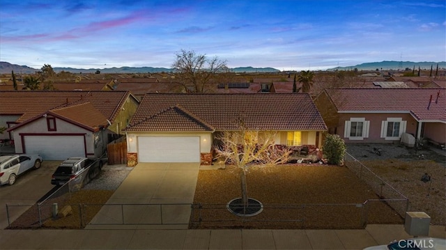 view of front of house with a garage, a tile roof, a mountain view, and concrete driveway