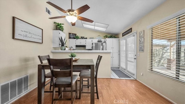 dining room with lofted ceiling, light wood-style flooring, a ceiling fan, visible vents, and baseboards