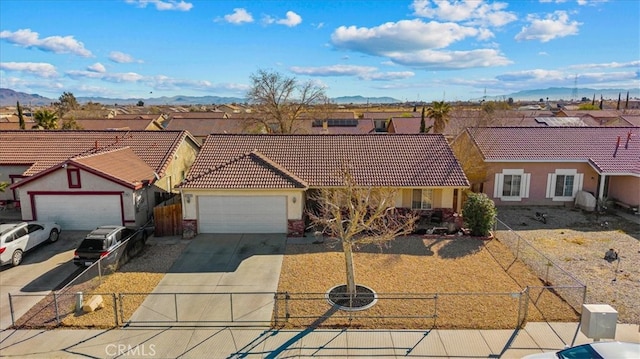 ranch-style house featuring concrete driveway, fence, a tiled roof, and an attached garage