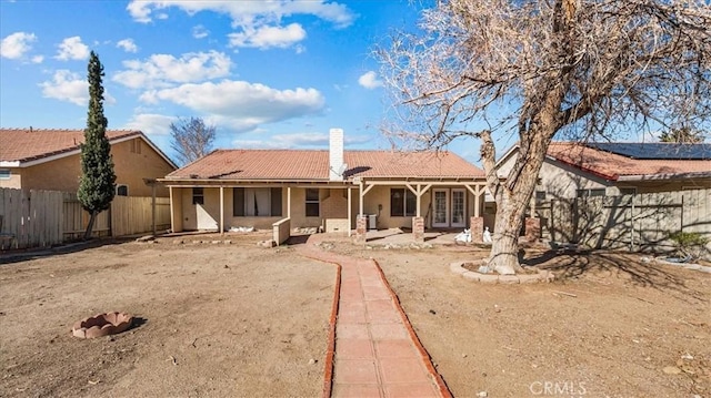 exterior space featuring a fenced backyard, a tiled roof, french doors, a chimney, and a patio area